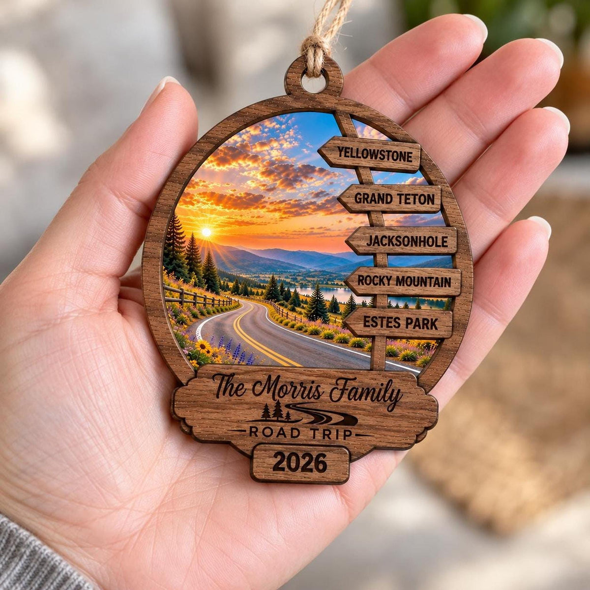 A person holds the custom wooden road trip ornament in the palm of their hand.